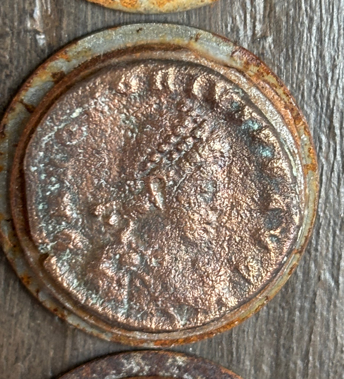 The middle ancient Roman coin is dated from 27 to 282 AD