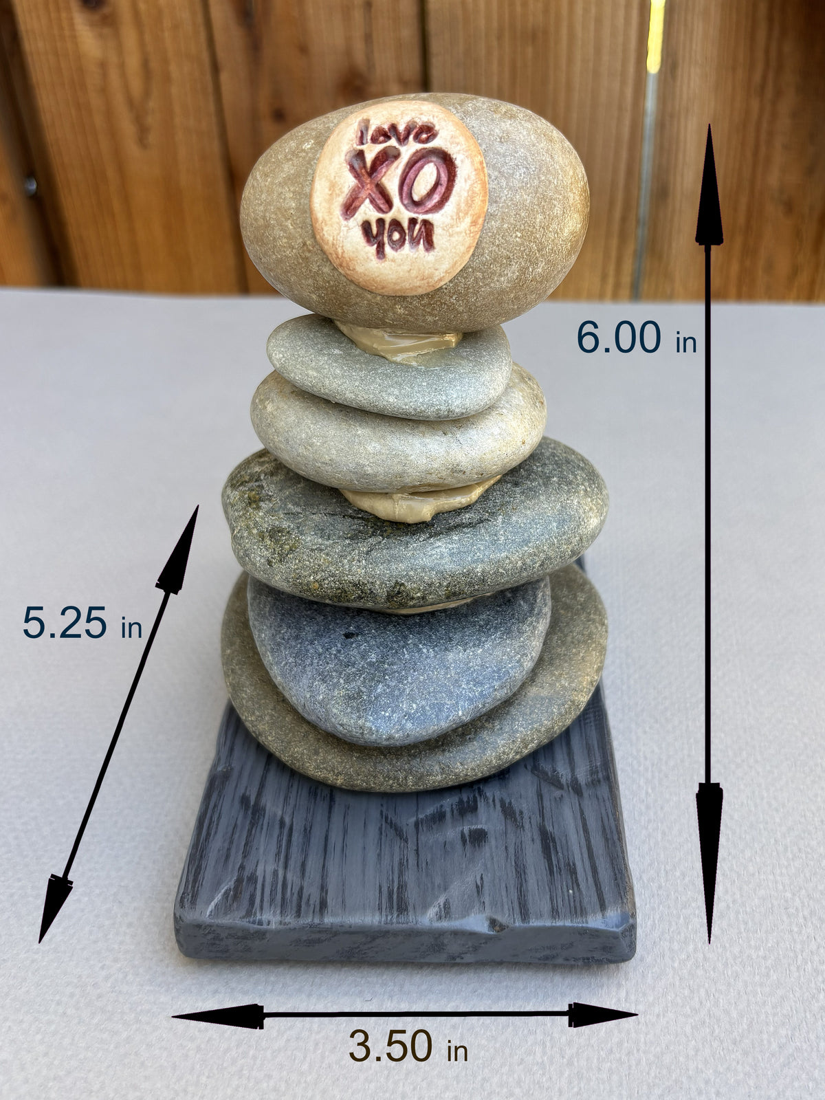 A small stacked stone sculpture on a rectangular base, with overlaid dimensions.