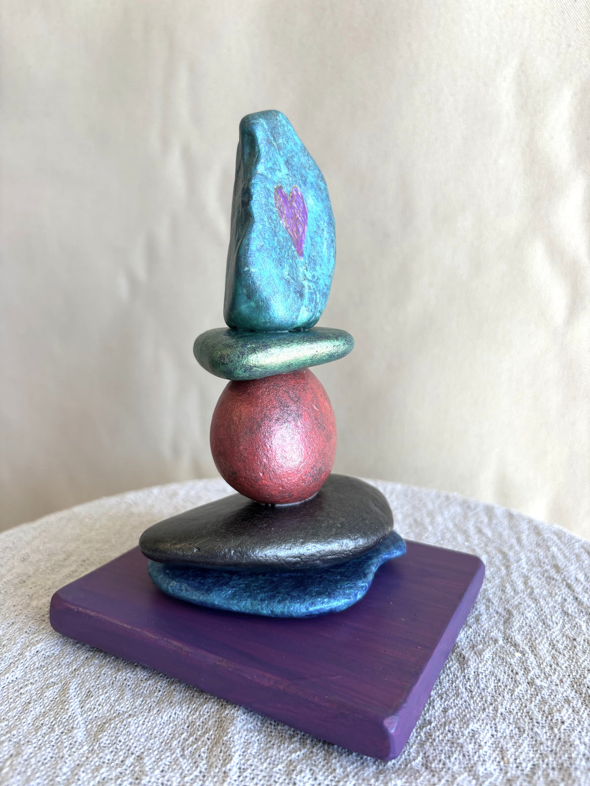 Beautifully colored river rock sculpture by Robert Schott showing a hand carved heart into the stone.