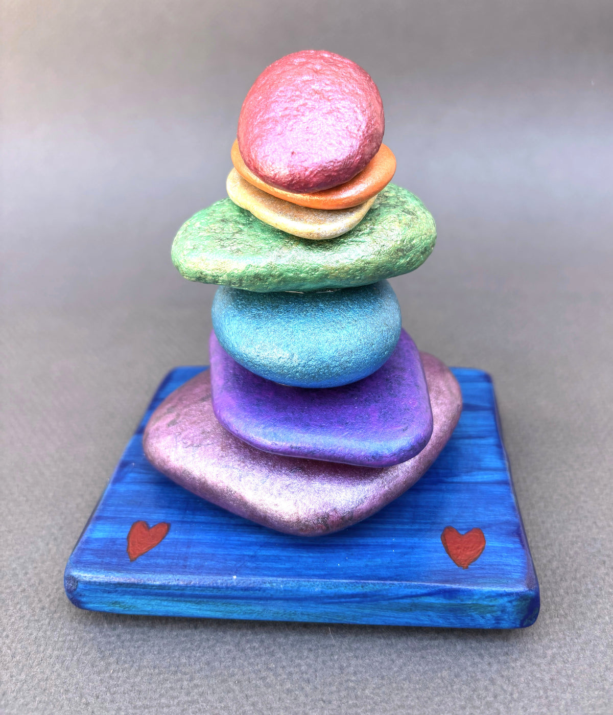 Front view of this seven colors of the rainbow on this stacked river rock cairn sculpture by Robert Schott