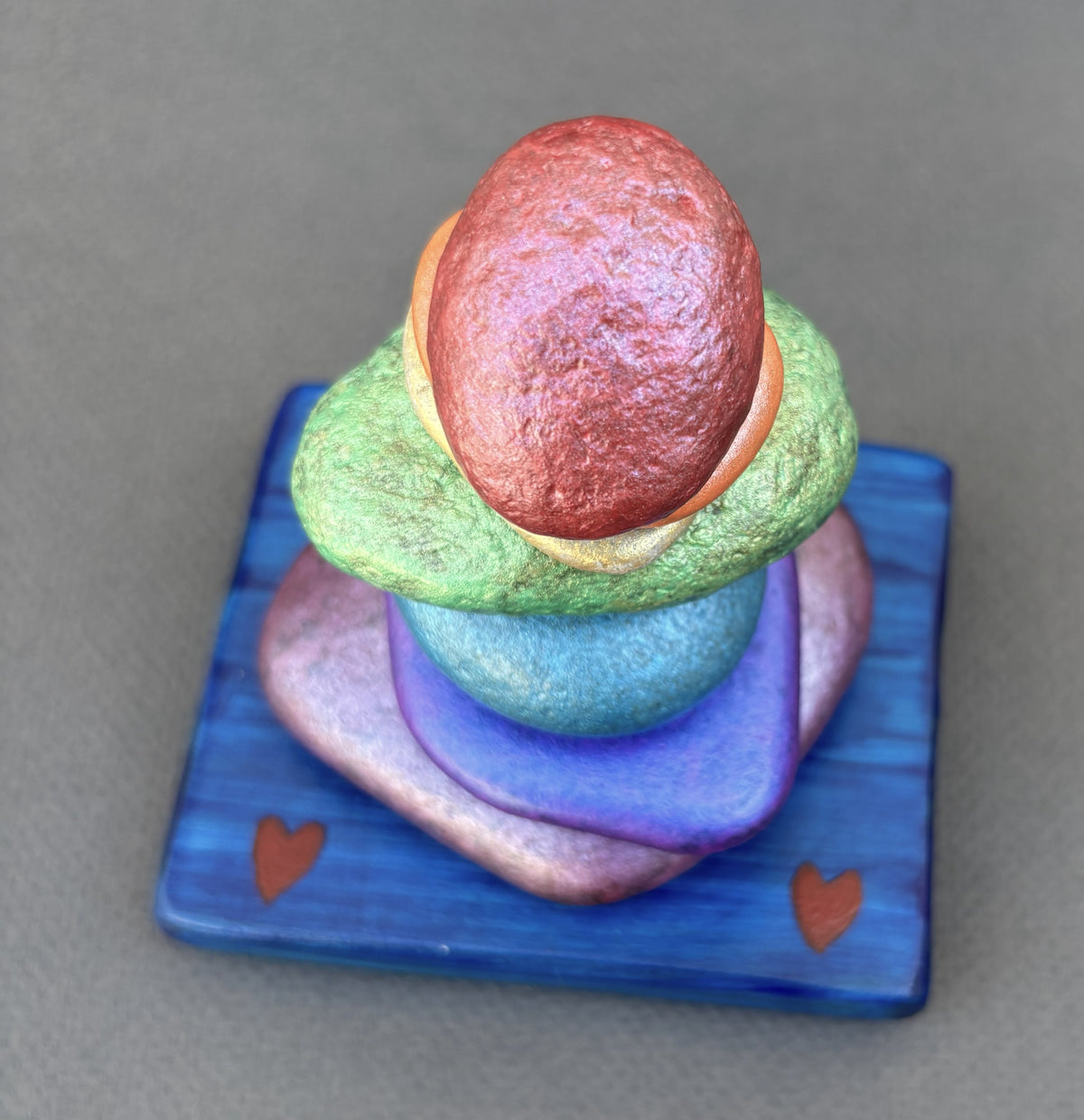 Top view of seven colored rocks for a rainbow cairn sculpture by Robert Schott