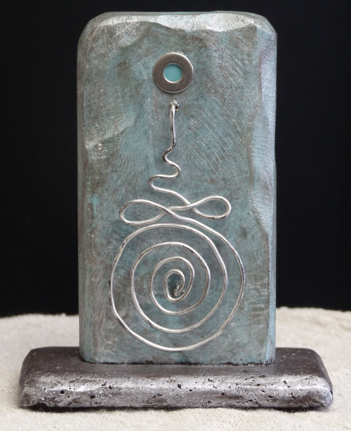Buddhist sculpture depicting a Buddhist Unalome symbol one one side, the sculpture is titled 'The Path' by Robert Schott.