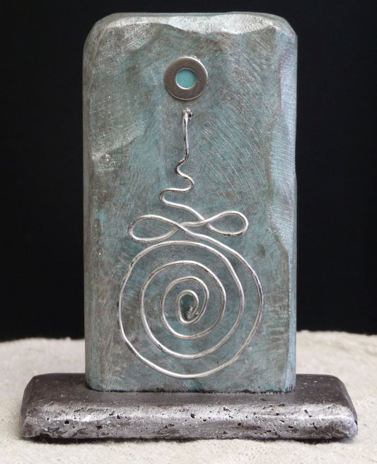 Buddhist sculpture depicting a Buddhist Unalome symbol one one side, the sculpture is titled 'The Path' by Robert Schott.