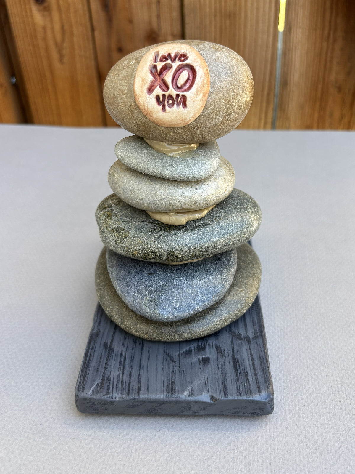 A small river rock sculpture on a dark wood  base.