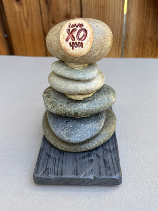 A small river rock sculpture on a dark wood  base.