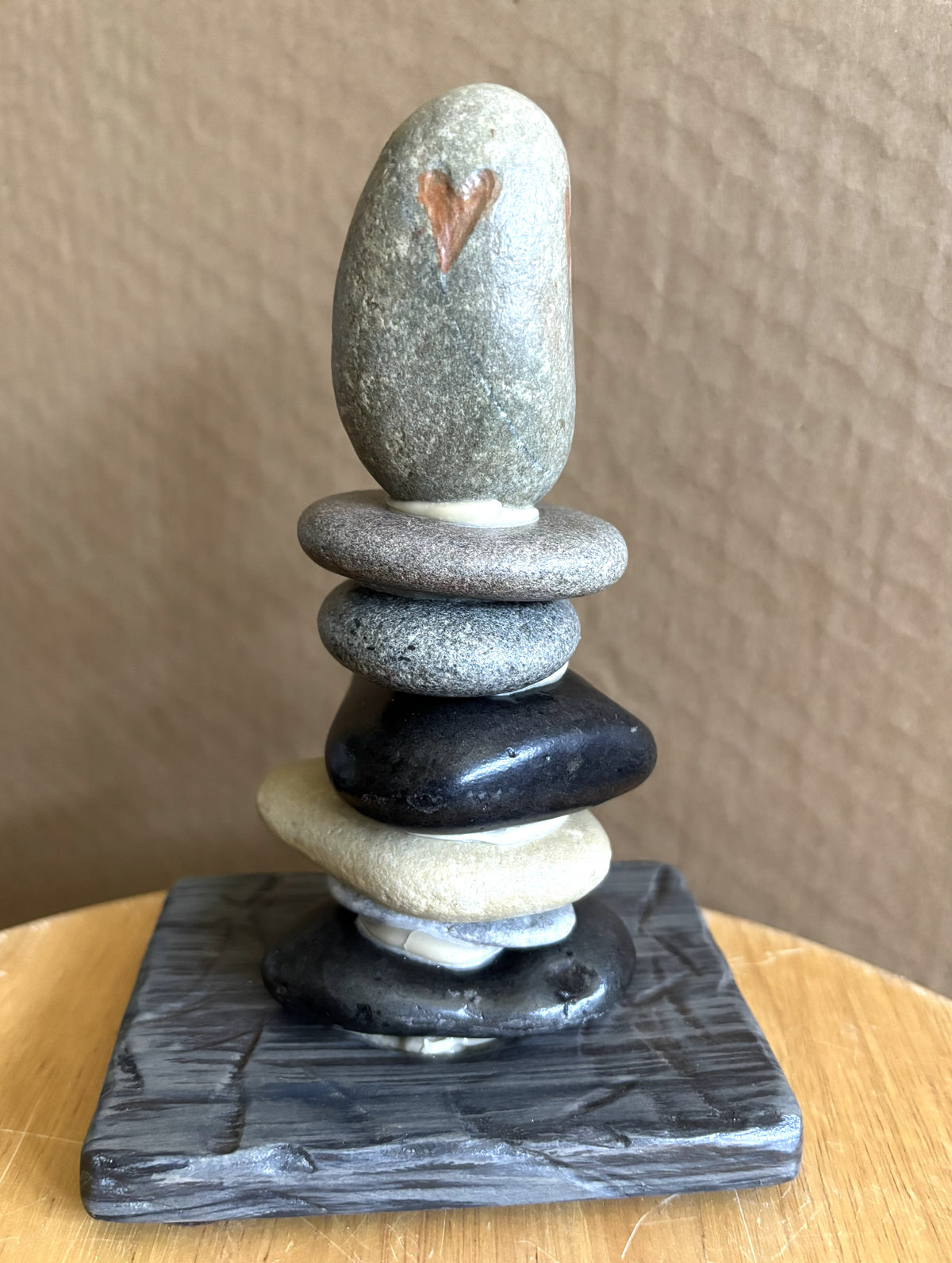 Seven river rocks stacked with a red heart etched in top stone.