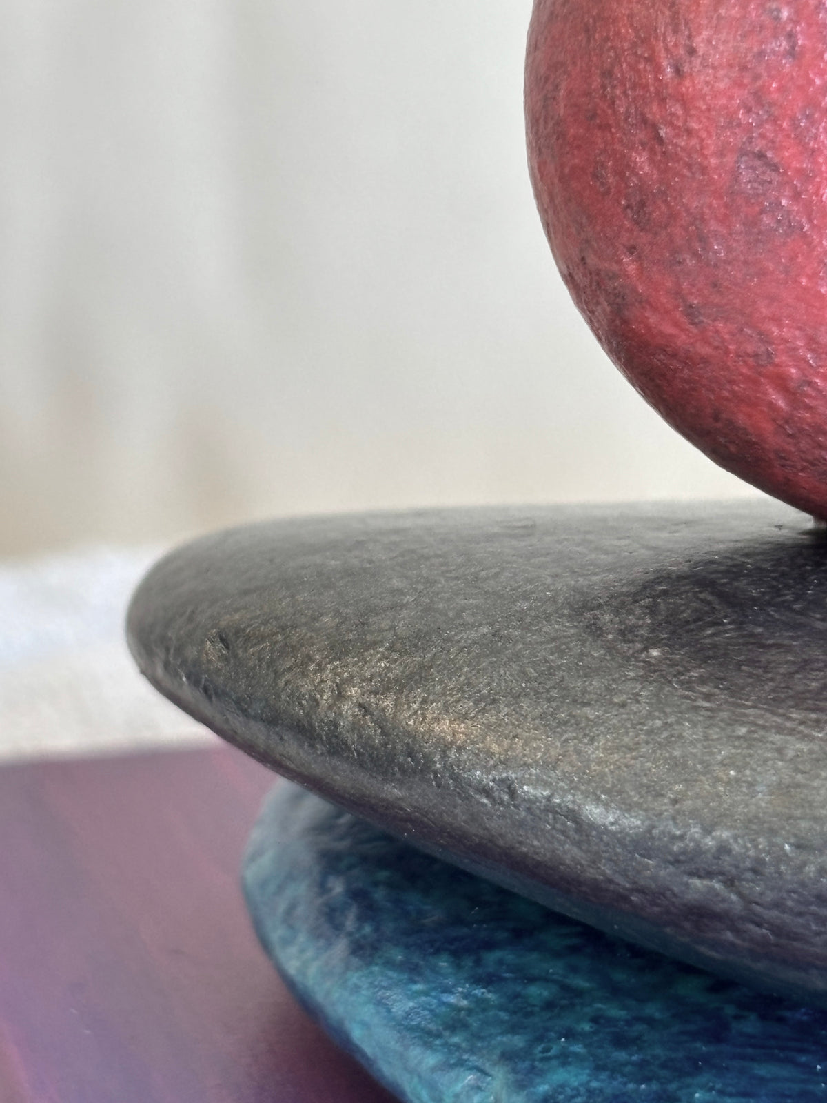 A closeup detail of three vibrantly colored stones on a sculpture by Robert Schott